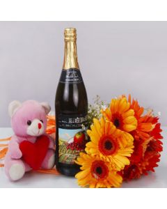 Hamper of bunch of 10 gerberas along with a branded wine bottle along with 6 inches of teddy bear.